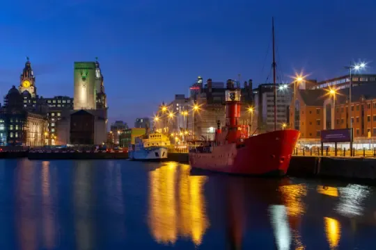 Liverpool waterfront at dusk, with the Royal Liver Building and a red lightship in the dock