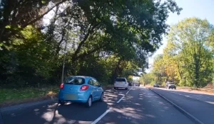 Cars on a tree-lined dual carriageway in sunshine